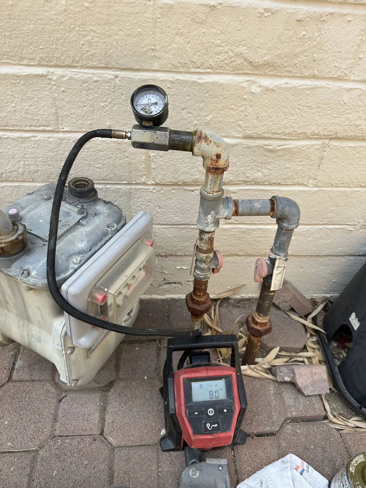 Gas line pressure testing at a meter with gauge and manometer during a repair