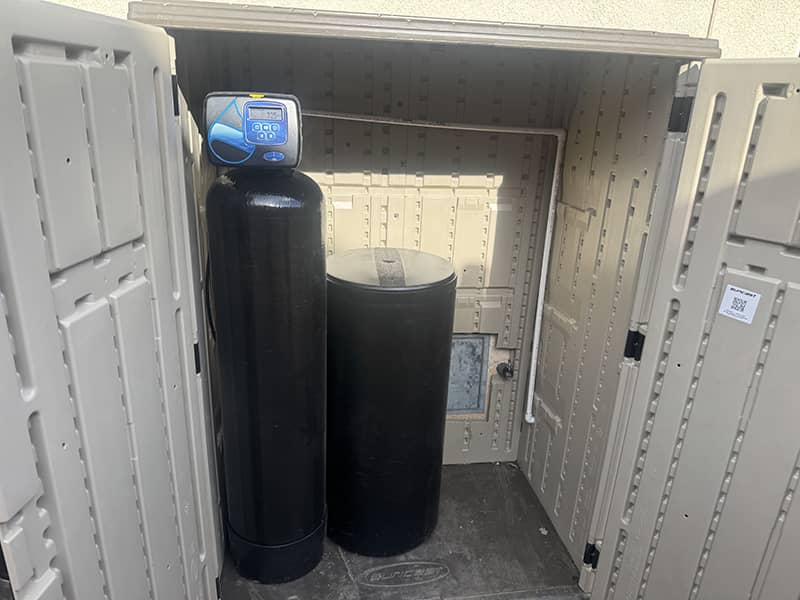 Whole-house water softener installed in an outdoor enclosure