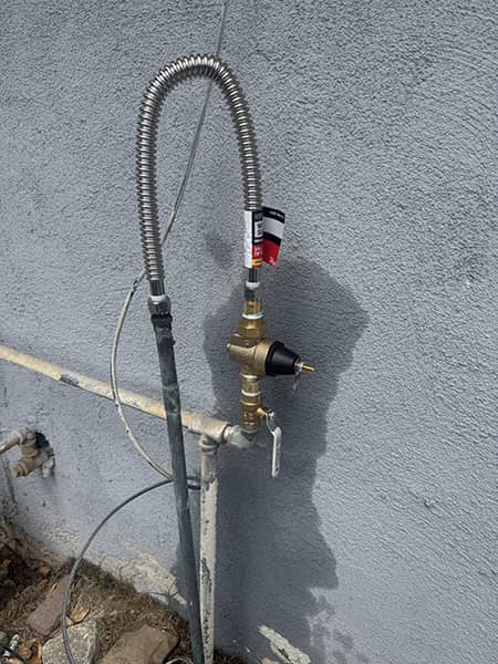 New brass pressure regulator and water line installed on a home in the High Desert