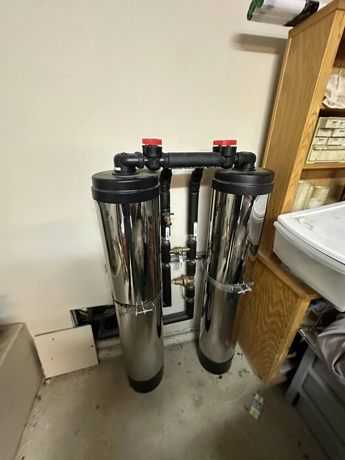 Twin whole-house water filtration tanks installed in a garage
